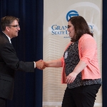Doctor Smart shaking hands with an award recipient in a coral sweater